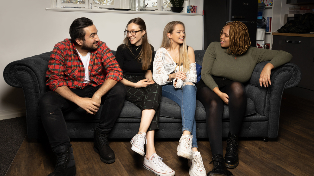 four people on a sofa talking