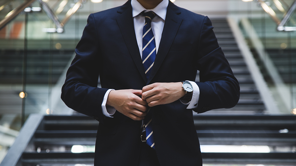 man buttoning up blazer