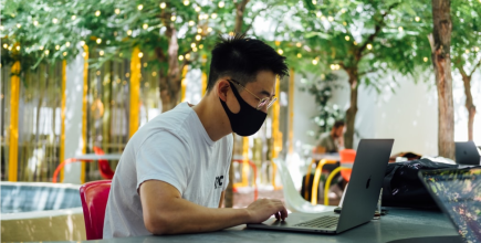 man using laptop while wearing mask